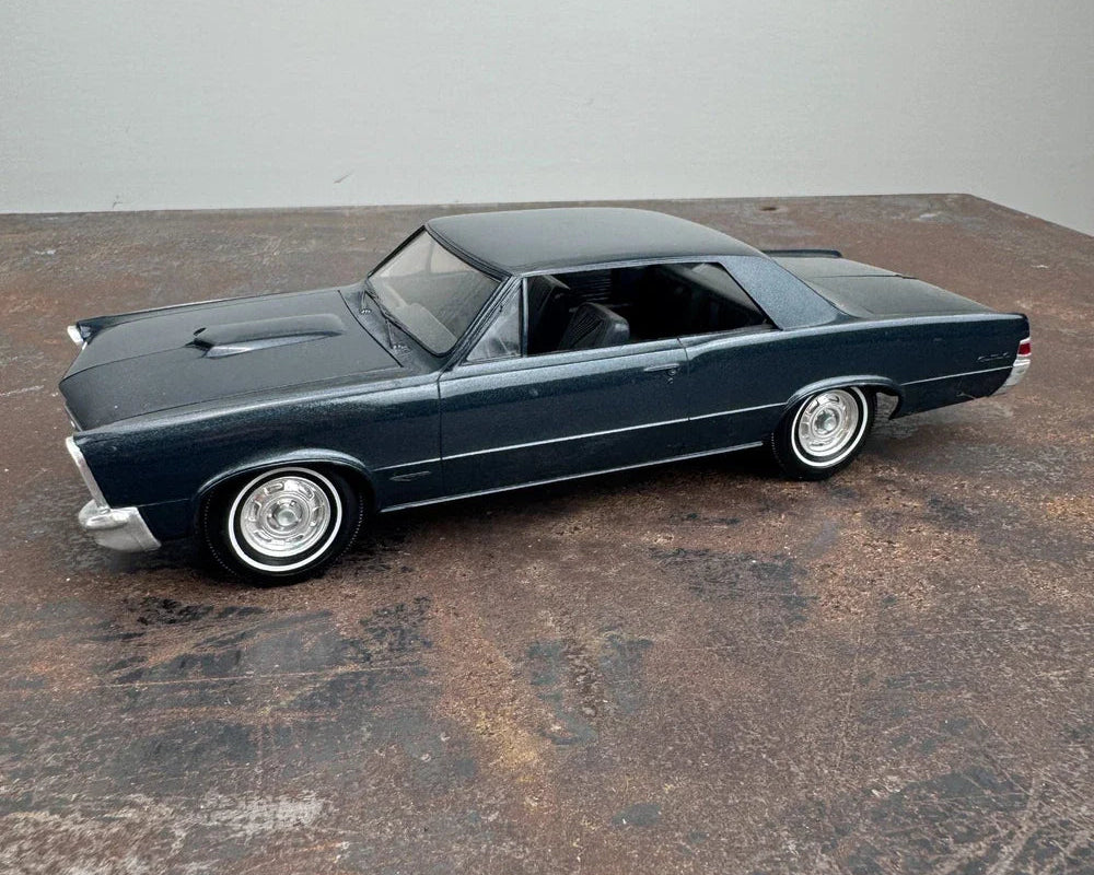 Model of a classic car on a textured surface with a neutral background